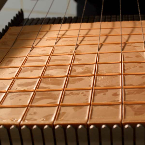 une grille qui découpe une plaque de chocolats pour La Boîte à biscuits