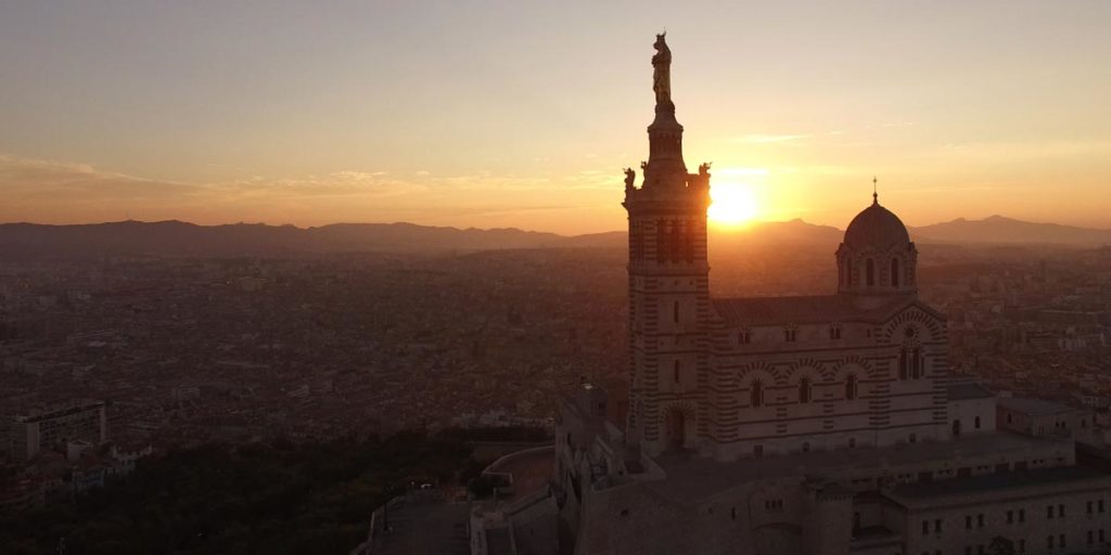 vue drone d'un coucher de soleil derrière Notre-Dame de la Garde à Marseille