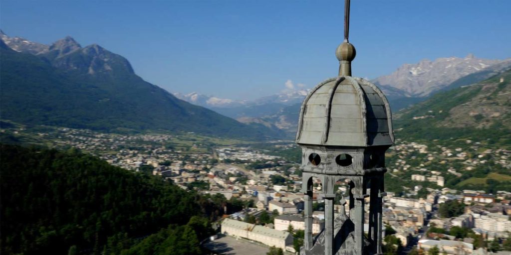 survol drone du clocher de l'église d'Embrun avec vue sur la vallée