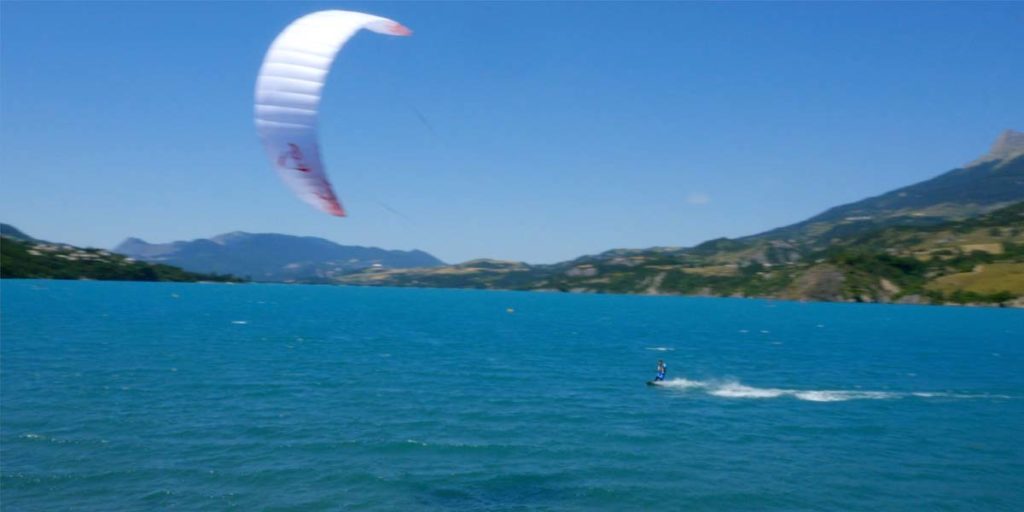 plan drone d'une personne qui fait du kitesurf sur le lac de Serre-Ponçon dans les Hautes-Alpes