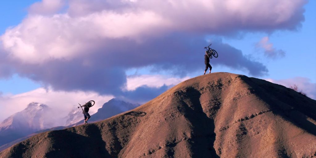 deux personnes portent leur VTT Lapierre en haut d'une colline