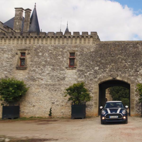 une voiture Mini Cooper bleue dans la cour d'un château de Dordogne