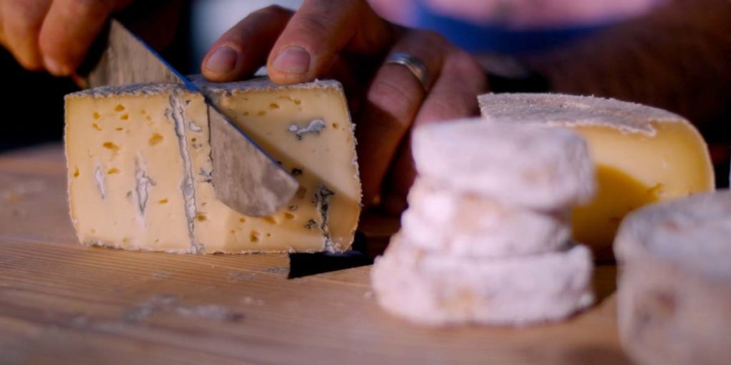 une personne coupe un fromage des Hautes-Alpes au salon de l'agriculture