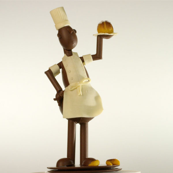 sculpture en chocolat représentant un bonhomme pâtisser portant un gâteau