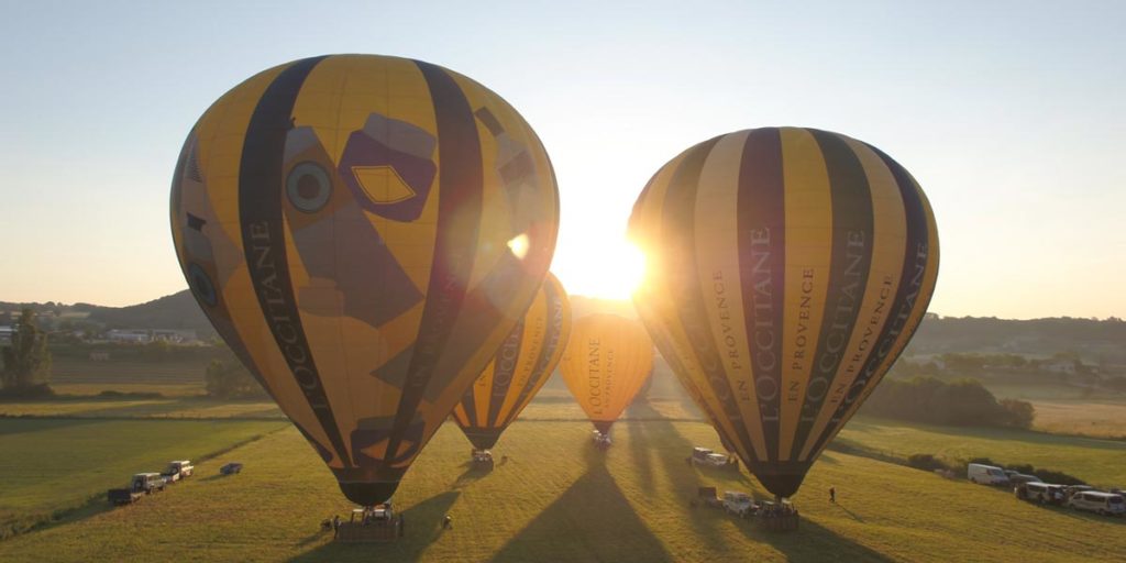 quatre montgolfières jaunes aux couleurs de l'Occitane en Provence sont sur le point de décoller, au petit matin