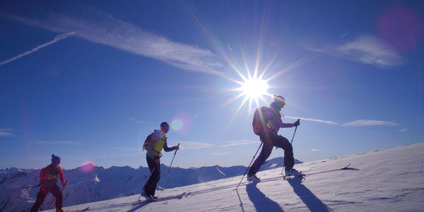 trois skieurs de randonnée grimpent au sommet des Orres lors d'une matinée ensoleillée