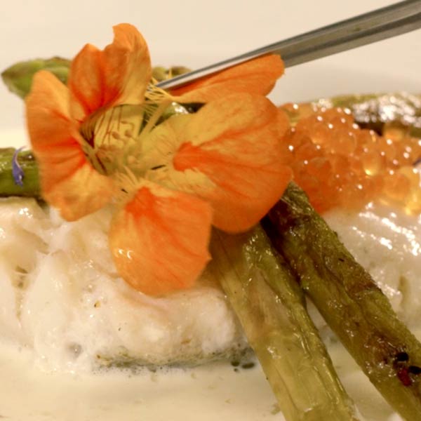 fleur orange posée délicatement sur un plat de poison et asperges au restaurant l'Auberge de la Méouge